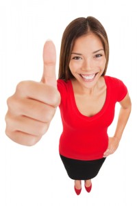 Smiling woman in a red top and black skirt giving a thumbs up on a white background