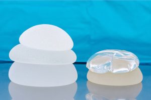 Stack of silicone breast implants on a blue backing.