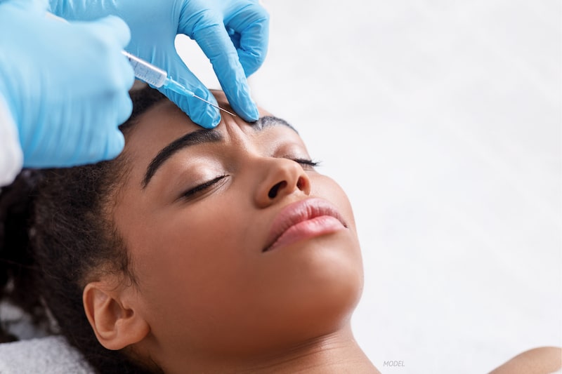 Woman getting BOTOX-type injection between her eyebrows.