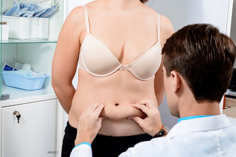 Surgeon pinching female patient's full midsection.