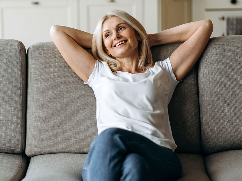 Middle aged woman happily leaning back on a sofa