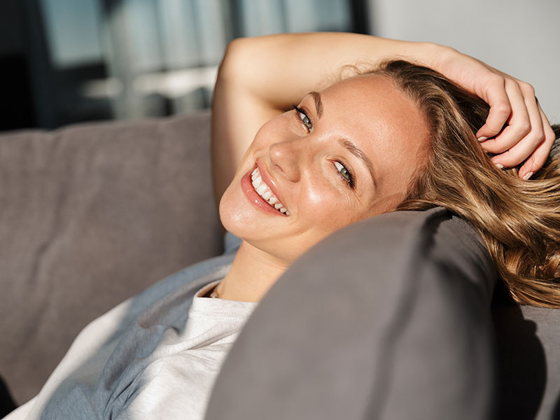 Headshot of young adult woman leaning back on a sofa