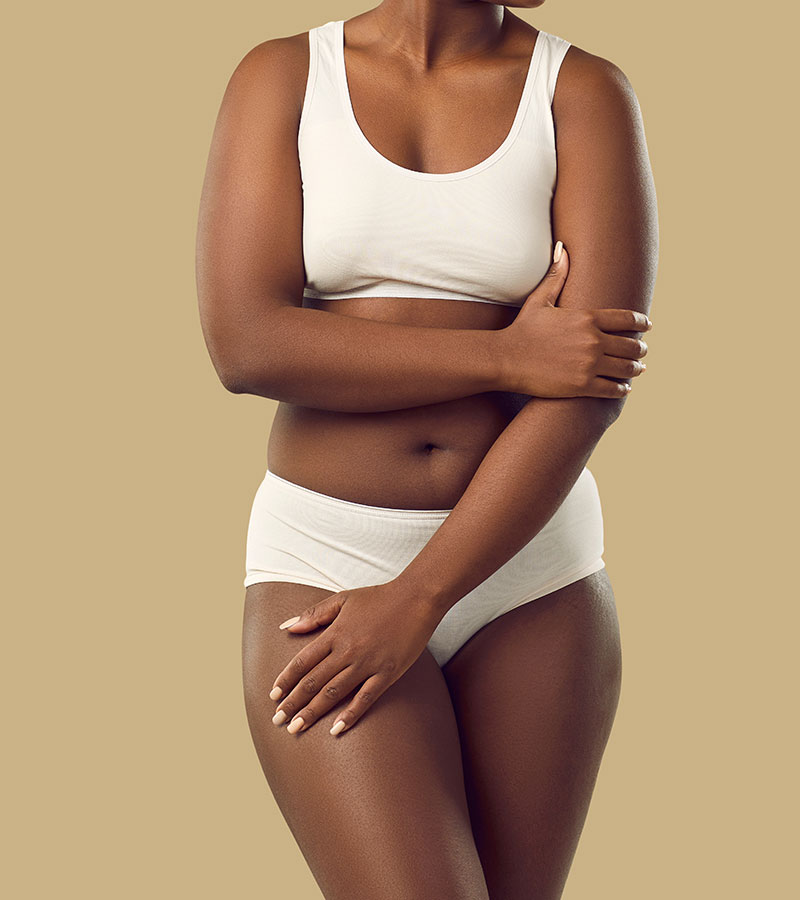 Mid body shot of a plus sized female model in white undergarments
