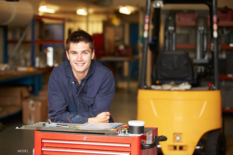 Young man standing in a maintenance shop.