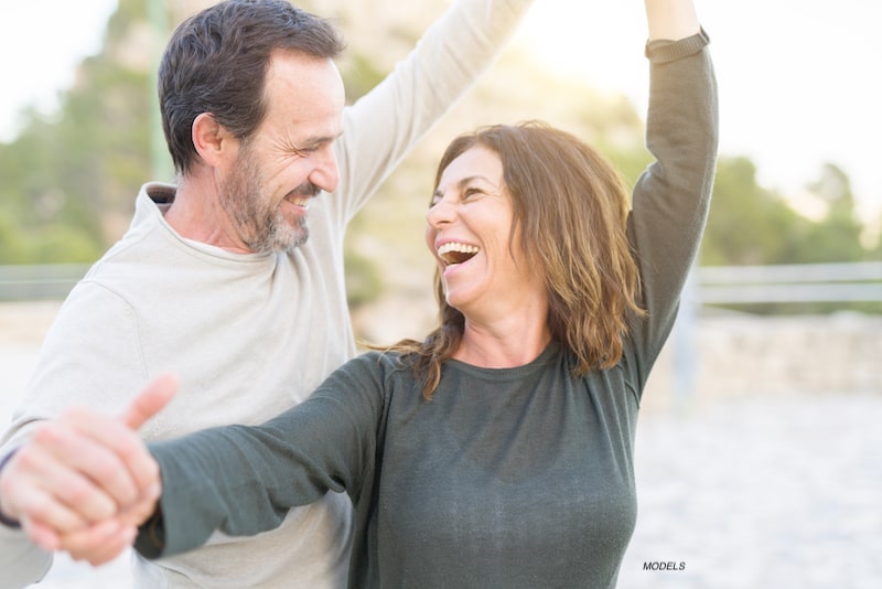 Attractive middle-aged couple smiling and laughing together while at a park.