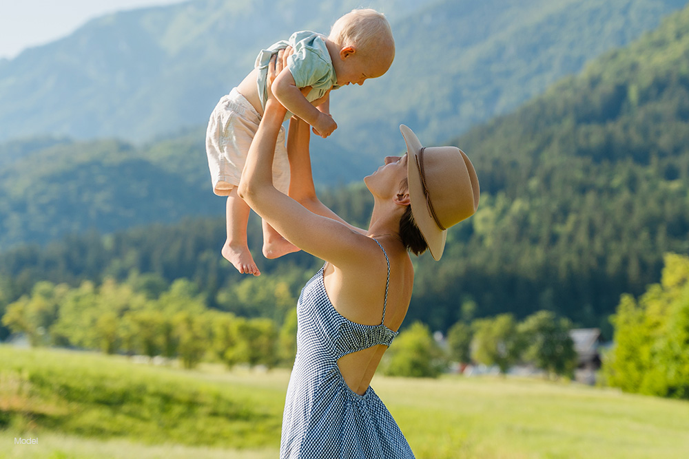 A woman holding a baby in a grassy field